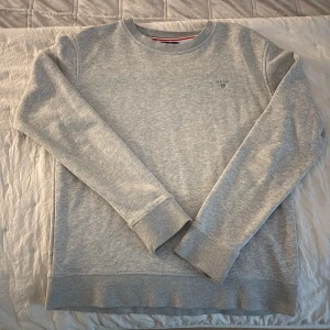 Ljusgrå sweatshirt från GANT - Helt ny GANT-tröja, aldrig använd. Köpte tröjan för några år sedan för ca 1 000 kr och känner att jag vill bli av med den för att den ligger bara i garderoben. Det är en äldre modell med unik design. Säljes för 150 kr, pris kan diskuteras.