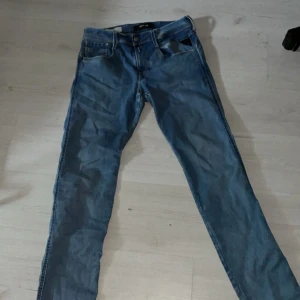Blå Replay jeansbyxor herr W30 - Säljer ett par klassiska blå jeansbyxor från Replay i modellen W30. Byxorna har normal passform, raka ben och fem fickor. Snygga detaljer med Replay-logga vid fickan och metallknapp framtill.