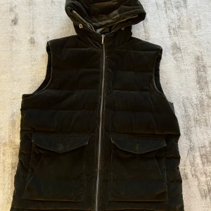 Stenströms Brun manchester dunväst - Säljer en svart dunväst från Stenströms i manchestertyg. Västen har huva, dragkedja framtill och två stora fickor med lock. Nypris ca 4000 
