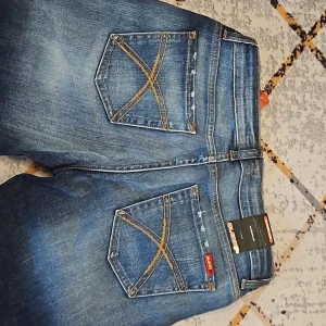 Blå jeansbyxor från BlendShe - Ett par klassiska blåjeans med snygga kontrastsömmar på bakfickorna är till salu. Byxorna har en normal passform och raka ben med en vid skärning nedtill. Perfekt för dig som älskar jeansens tidlösa look.Vikt: 500 g