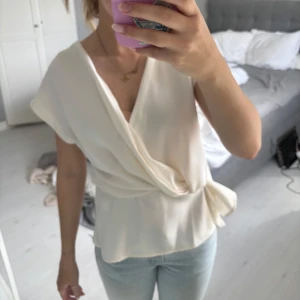 Vit omlottopp med knyt från Zara - Populär  omlottopp från Zara med knyt i sidan. Toppen har korta ärmar och djup v-ringning, vilket ger en elegant och modern look. Perfekt att matcha med jeans eller kjol nu till sommaren 💓