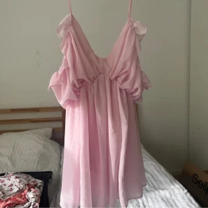 Ljusrosa volangklänning med smala axelband - Supersöt ljusrosa klänning med volangdetaljer och smala axelband🩷. Klänningen har en luftig passform och är tillverkad i ett lätt, flowy material som ger en romantisk känsla. Perfekt för sommarens alla tillfällen! Så sjukt snygg! Första bilden är lånad men det är samma!!! Har "shorts" i sig🩷🩷 passar allt från xs-m kanske även L!!