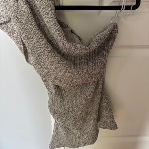 Beige ribbad one shoulder topp - Trendig beige one shoulder topp med ribbad struktur. Klänningen har en kroppsnära passform och är perfekt för dig som gillar en stilren och modern look. Materialet är mjukt och stretchigt för extra komfort. Storlek L men passar m