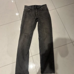 Grå jeans från Jack & Jones - Säljer ett par grå jeans från Jack & Jones, modell Comfort/Mike. Jeansen har klassisk femficksdesign, normal passform och stängs med knapp och dragkedja. Perfekta för dig som gillar en enkel och stilren look.