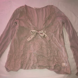 Ljusrosa blus med rosett från Odd Molly - Supersöt ljusrosa blus från Odd Molly med broderade detaljer och spets längs sidorna. (Hål I höger arm som man ser i bild 2) tror den e storlek s