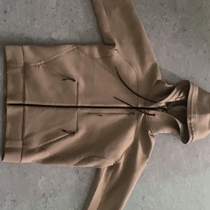 Hugo boss zip hoodie - Säljer en beige hoodie med dragkedja framtill och två fickor med dragkedja. Jackan har huva och är långärmad, perfekt för lager-på-lager-stil. Enkel och stilren design som passar till det mesta. Original pris 2400