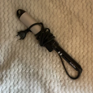Locktång från BaByliss - Locktång med svart handtag och ljusgrå cylinder från BaByliss. Utrustad med sladd och europeisk kontakt. Perfekt för att skapa snygga lockar och volym i håret. Köpt för typ 2-3 år sen men aldrig använd. Ca 42 mm i diameter💕