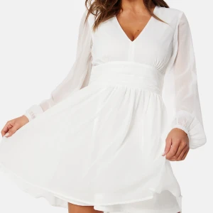 Studentklänning! Vit chiffongklänning med v-ringning och knyt i midjan - Superfin vit kortklänning i chiffong med v-ringning, långa transparenta ärmar och markerad midja med knytband bak. Perfekt för studenten. Luftig och lätt. Oanvänd! 