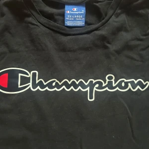 Svart t-shirt från Champion - Svart t-shirt från Champion med stort logotryck över bröstet. Klassisk passform och rund halsringning. Passar både killar och tjejer. Perfekt för en avslappnad och sportig stil!💓