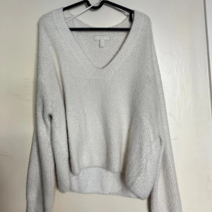Vit stickad v-ringad tröja från H&M - Mysig vit stickad tröja från H&M med v-ringning och långa ärmar. Perfekt för lager-på-lager och passar till många olika stilar. Tröjan har en avslappnad passform och ribbade muddar.                                                       