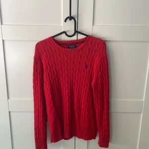 Röd kabelstickad tröja från Polo Ralph Lauren - Säljer en klassisk röd kabelstickad tröja från Polo Ralph Lauren. Tidlös och stilren design. Originalpris ~950kr. Notera att den är i barn storleken L(14-16).
