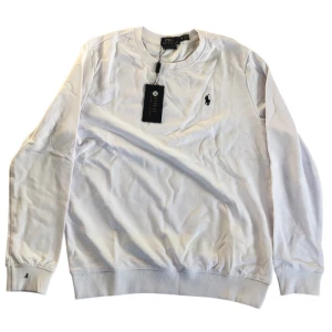 Vit långärmad tröja från Polo Ralph Lauren - Säljer en klassisk vit långärmad tröja från Polo Ralph Lauren med rund halsringning och broderad logga på bröstet. Tröjan har ribbade muddar vid ärmslut och nederkant. Perfekt för en stilren look.