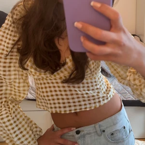 Gul topp - Trendig croppad blus med gula och vita rutor. Blusen har långa puffärmar med resår vid ärmslut och smockad rygg för extra komfort. Perfekt för vår och sommar, och ger en fräsch look till jeans eller kjol❤️