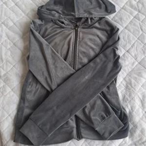 Grå hoodie med dragkedja från Gina Tricot - Mjuk och skön grå juicy tröja från Gina Tricot i storlek S. Tröjan har dragkedja framtill, huva och långa ärmar. Perfekt för en avslappnad stil.🩶 Ställ gärna frågor om ni behöver!
