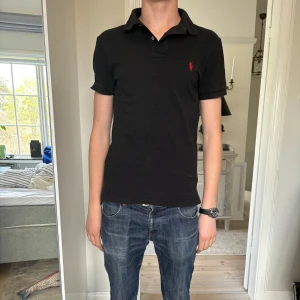 Ralph lauren pike  - Snygg svart Ralph lauren pike i mycket bra skick utan skador eller defekter. Inte använd så mycket. Killen på bilden är 180 cm och väger 65 kg. Pris kan diskuteras.