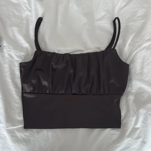 Svart croppad silkes topp med rynkade detaljer - Säljer en svart croppad silkes topp  med smala axelband och rynkade detaljer framtill.  Köpt från hm. 