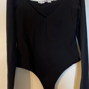 Svart långärmad body från NA-KD - Svart body med lång ärm och v-ringad hals från NA-KD. Snygg och enkel design som passar till många olika outfits. Tillverkad i mjukt material för en bekväm passform.