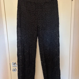 Svarta spetsbyxor - Säljer ett par svarta byxor i spets med rak passform. Byxorna har ett elegant mönster och är perfekta för dig som vill ha något extra till outfiten. Hög midja och mjukt material som ger en bekväm känsla.