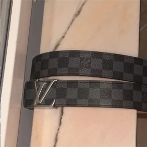 Svart fint bälte  - Säljer ett fint bälte med klassiskt rutigt mönster och silverfärgad buckle. Bältet har en stilren design och är tillverkat i skinn. Perfekt accessoar för att lyfta din outfit.