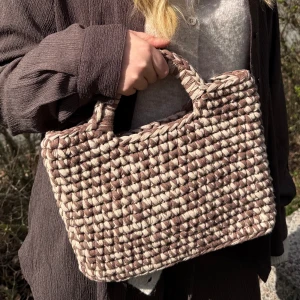 Beige och brun virkad handväska - En superfin handväska i virkat material med en mix av beige och brunt. Väskan har ett stadigt handtag och en rektangulär form, perfekt för att bära det viktigaste och lite till. Väldigt rymlig.  Superfin accessoar till din outfit! Kika gärna in vår Instagram @design.by.bela för andra modeller och väskor. Du kan även designa din egna utefter din färg!