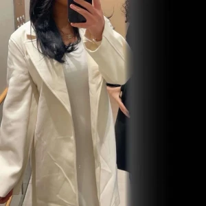 Vit kappa med bred krage - Säljer en stilren vit kappa med bred krage och lång ärm. Jackan har en klassisk rak passform och är perfekt för dig som vill ha en elegant look. Passar till många olika tillfällen. Pris kan diskuteras.