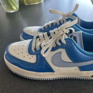 Wmns Nike Air Force 1, strl 38,5 - Säljer ett par Nike Air Force 1 sneakers i blått och vitt, användna men fortfarande hyfsatt bra skick! (Storlek 38.5) 