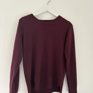 Vinröd stickad tröja från M&S Collection - Vinröd stickad tröja från M&S Collection med rund halsringning. Klassisk modell med långa ärmar och ribbade muddar. Perfekt till en kallare sommardag!