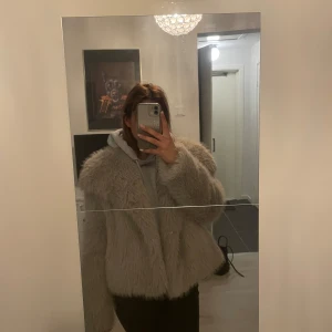 Beige pälsjacka - Säljer en fluffig och trendig beige pälsjacka med lång ärm. Jackan har en oversized passform och är perfekt för att hålla värmen under kyliga dagar. Enkel att styla till olika outfits och ger en lyxig känsla.