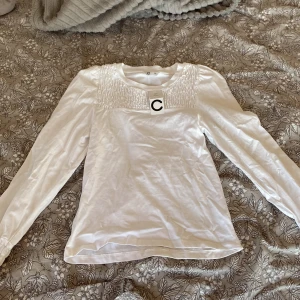 Vit långärmad topp från Cubus - Säljer en vit långärmad topp från Cubus med smockdetaljer vid axlar och ärmslut. Toppen har rund halsringning och är tillverkad i mjukt bomullsmaterial. Säljer pågrund av att den aldrig har använts därav lappen är kvar!❤️ NY PRIS ÄR 399 