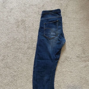 Blå jeansbyxor från G-Star RAW - Säljer ett par klassiska blå jeansbyxor från G-Star RAW med normal passform. Byxorna har fem fickor, dragkedja och knapp framtill samt diskreta söm-detaljer på bakfickan. Perfekta för dig som gillar stilrena jeans. Storlek: W30 L32