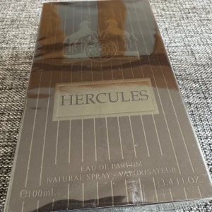 Hercules Eau de Parfum 100ml - Hercules från Maison Alhambra är en unisexparfym med tydliga noter av tobak, varm krydda, vanilj och amber. Flaskan är mörkbrun med silverdetaljer och har en elegant, modern form. Parfymen har även inslag av kanel, trä, sötma och mysk.