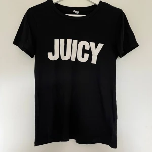 Svart Juicy Couture t-shirt - Svart t-shirt från Juicy Couture med stor vit JUICY-print på bröstet. Klassisk rund hals och korta ärmar. Inga tecken på användning