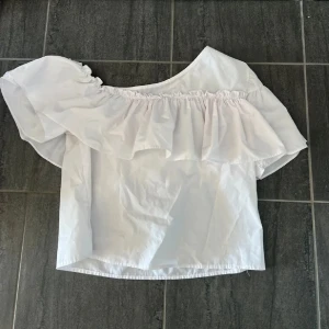 Offshoulder topp - Supersöt vit topp med offshoulder och stor volang längs halsen. 