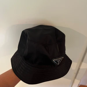 Svart bucket hat  - Snygg svart bucket hat. Hatten har en stilren form ger en cool och modern vibe. Perfekt accessoar för att lyfta din stil.