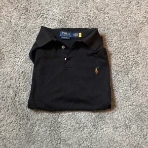Svart pikétröja från Polo Ralph Lauren - Svart pikétröja från Polo Ralph Lauren .knappt använd. Köpt för 899 kronor. Passar perfekt till golfen eller bara på vanliga sammanhang.