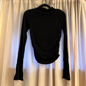 Svart polotopp - Svart långärmad polotopp från Gina Tricot i storlek S. Toppen har en tight passform och rykad detalj längs sidan som ger en snygg effekt.✨✨