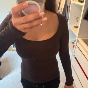 Brun långärmad topp med djup urringning - Brun topp med lång ärm. ( tröjan är inte smutsig, det är spegeln )