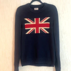Mörkblå stickad tröja med Union Jack - Snygg mörkblå stickad tröja med Union Jack-flagga i rött, vitt och blått på bröstet.De är i nyskick inga skavanker använt 5 gånger, passar både S och M . Perfekt för dig som gillar klassisk brittisk stil och vill sticka ut lite extra.Hör av er vid funderingar!