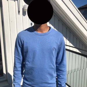 Blå långärmad tröja Polo Ralph Lauren köpt direkt från rom - Snygg blå långärmad tröja från Polo Ralph Lauren i klassisk design. Tröjan har rund hals och diskret logga broderad på bröstet. Tillverkad i mjuk bomull som är skön mot huden. Perfekt för dig som gillar stilrena och tidlösa plagg.