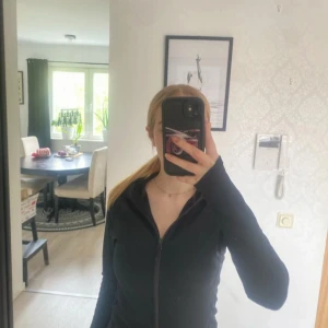 Svart hoodie med dragkedja - Svart hoodie från Everest med hel dragkedja framtill och huva. Tröjan har långärmade ärmar och två sidofickor med dragkedja. Perfekt för träning. Materialet är mjukt och känns skönt mot huden.