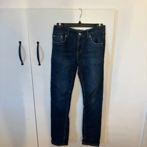 Levi's 512 Slim Taper jeans blå - Snygga Levi's 512 Slim Taper jeans i mörkblå denim. Klassisk femficksmodell med smal passform och avsmalnande ben. Tydliga kontrastsömmar och ikonisk läderpatch bak i midjan. Perfekta för dig som gillar en modern och clean look.