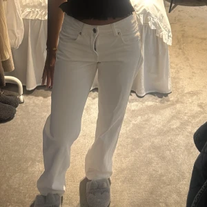 Vita raka jeans - Säljer ett par vita jeans. Byxorna har klassisk femficksdesign, knapp och dragkedja framtill samt bälteshällor💞Storlek 32 men skulle säga att det är lite större i storleken
