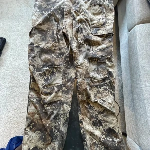 Cargobyxor med camouflage-mönster - Säljer ett par cargobyxor med flera fickor och grymt camouflage-mönster i bruna, beige och svarta toner. Perfekta för dig som gillar outdoor eller streetstyle. Byxorna har en loose passform och är tillverkade i slitstarkt material.