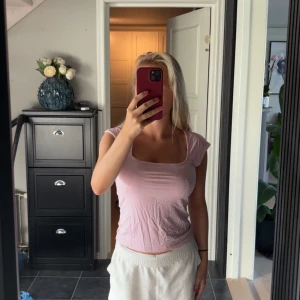 Ljusrosa croppad linnetopp - Säljer en ljusrosa croppad linnetopp med fyrkantig ringning och korta ärmar. Toppen har en enkel och clean design som är perfekt för att matcha med jeans eller shorts. Materialet känns mjukt och lätt mot huden.