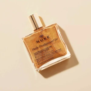 Nuxeolja - Glittrande olja från Nuxe i en lyxig fyrkantig glasflaska med guldfärgat lock. Oljan har en gyllene, skimrande finish som ger glow till ansikte, kropp och hår. Innehåller botaniska oljor och passar alla hudtyper. Perfekt för dig som vill ha extra lyster. Nypris 580. Helt ny!