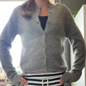 Grå kofta från Gina Tricot XS - Mysig grå kofta från Gina Tricot i storlek XS. Koftan har rund hals, långa ärmar och knappar hela vägen framtill. Materialet är fluffigt och stickat, perfekt för kyliga dagar. Enkel och stilren design som funkar till många olika outfits.