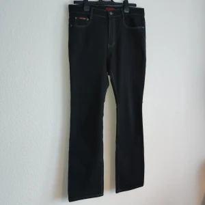 Svarta jeans från H&L - Snygga svarta jeans från H&L med klassisk femficksdesign. De har en rak passform och är perfekta för en stilren look. Jeansen har en knappgylf och kontrasterande sömmar som ger en cool detalj.