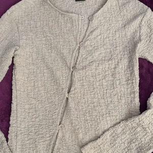 Blus  från Gina Tricot - Säljer en stilren blus  från Gina Tricot i storlek XS.  har en unik textur och knäppning framtill. Perfekt för lager-på-lager under kyligare dagar.