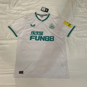 Newcastle United tredje-tröja 22/23 - Newcastle Uniteds tredje-ställ från säsongen 2022/23. Tröjan är helt ny med lappen kvar. Den är köpt på sportsdirect.com, och är alltså helt äkta.