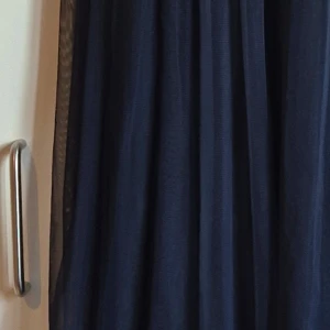 Mörkblå klänning med paljetter - Elegant mörkblå klänning med glittriga paljetter på överdelen. Perfekt för en festlig kväll. Klänningen har en flytande kjol som ger en vacker silhuett